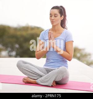 Trovare il suo centro. Foto a tutta lunghezza di una giovane donna che fa yoga all'aperto. Foto Stock