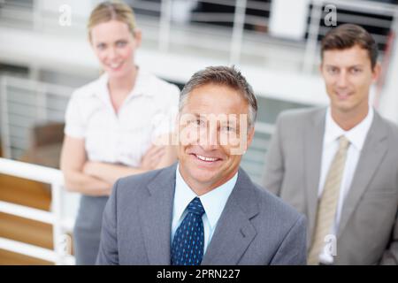 Trio dinamico di affari. Ritratto dall'alto di un dirigente esperto con i suoi colleghi alle sue spalle. Foto Stock