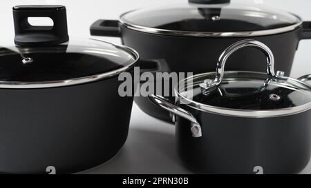 Set di pentole nere su sfondo bianco. Utensili per cucinare Foto Stock