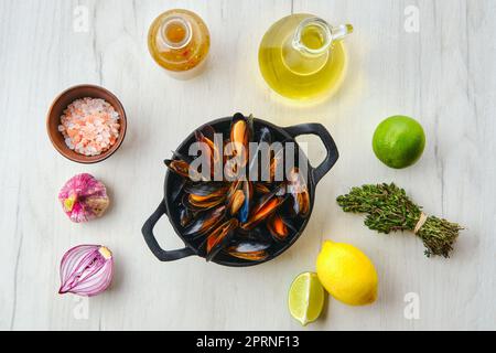 Vista dall'alto delle cozze non pelate in padella di ghisa con spezie ed erbe Foto Stock