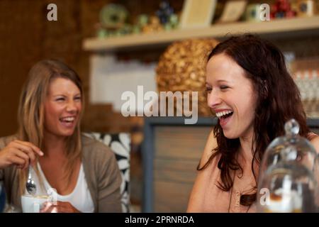 Recuperare i vecchi tempi. Due amiche che condividono una risata mentre si siedono in un bar Foto Stock