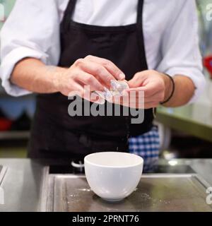 HES un artista in cucina. Uno chef prepara con cura un pasto gourmet Foto Stock