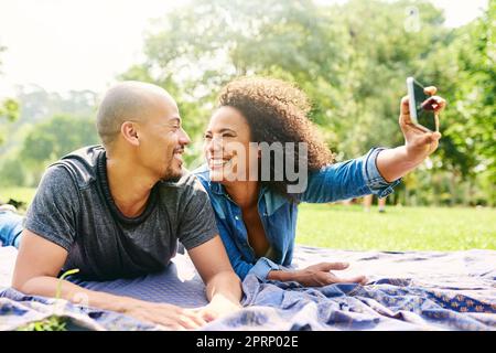 E' stata una splendida giornata, ora per un selfie. una giovane coppia bellissima trascorre la giornata in un parco pubblico Foto Stock