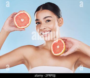 Pompelmo, cura della pelle, viso e dieta benessere la mantiene felice e sana per la salute della pelle, mangiare frutta sana con nutrizione. Ritratto di una bella donna in studio su uno sfondo blu Foto Stock