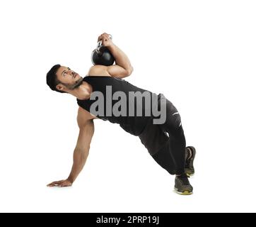 Intensificando la sua routine di fitness. Studio di un giovane uomo in forma che si allenava con una campana del bollitore su uno sfondo bianco. Foto Stock