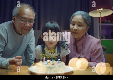 I nonni e la madre asiatiche felici di famiglia celebrano la festa di compleanno con la torta Foto Stock