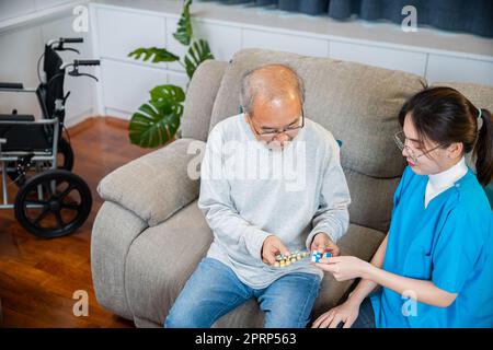 Medico asiatico con visita medico senior paziente di sesso maschile consultare il dosaggio della medicina a casa Foto Stock