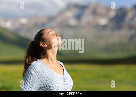 Donna rilassata che respira aria fresca in montagna una giornata di sole Foto Stock