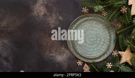 Ambiente da tavolo festivo con rami di abete e decorazioni rustiche natalizie con vista scura dal piano del tavolo Foto Stock