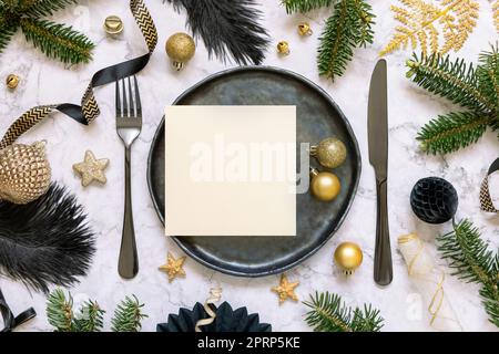 Tavolo di Natale nero e dorato con un biglietto da visita, ornamenti e rami di abete. Mockup Foto Stock