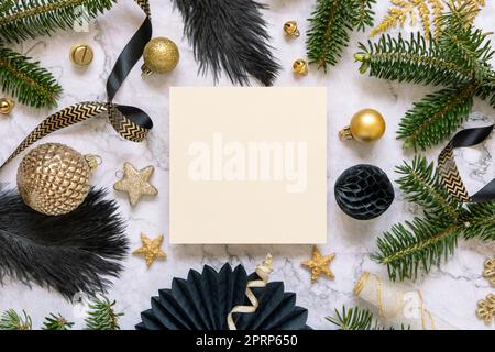 Scheda vuota tra decorazioni natalizie nere e dorate e vista dall'alto dei rami di abete Foto Stock