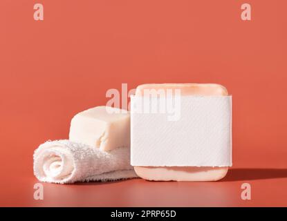 Saponette fatte a mano con etichetta vuota e piccolo asciugamano rosa per primi piani e ombre dure Foto Stock