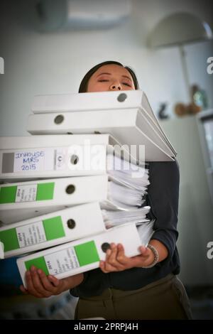 Sarà una giornata impegnativa. Ritratto di una donna d'affari faticosa che lotta per portare un mucchio di file in ufficio Foto Stock