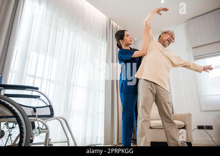 L'anziano ama allenarsi con il fisioterapista per le braccia distese a casa Foto Stock