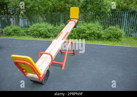 Altalena a forma di tavola di legno in un parco giochi vuoto all'aperto, area giochi per bambini Foto Stock