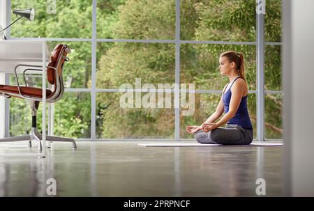 Trovare il suo centro. Scatto completo di una donna sportiva che pratica yoga a casa. Foto Stock