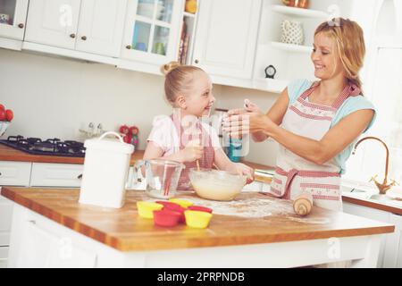 Questo è molto divertente. Carina bambina che si cucina con la mamma. Foto Stock