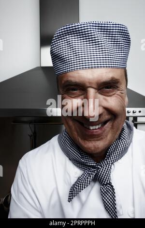 Chef senior allegro di fronte alla cappa di ventilazione. Primo piano ritratto di un cuoco anziano allegro di fronte alla cappa di ventilazione. Foto Stock