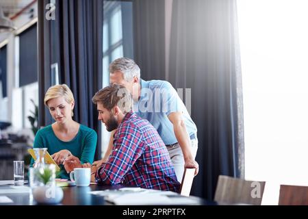 Un gruppo di colleghi che discutono su un tablet digitale. Foto Stock