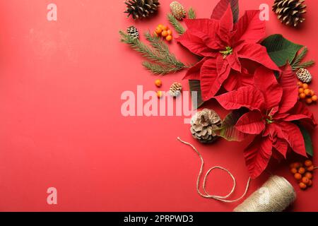 Composizione piatta con poinsettie (fiori di Natale tradizionali) e decorazioni su sfondo rosso. Spazio per il testo Foto Stock