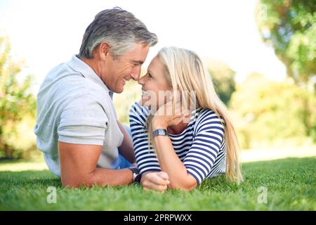 Approfittando di questa bella giornata, una coppia matura affettuosa che si trova faccia a faccia nel parco. Foto Stock