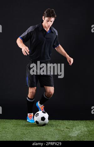 Cogliete l'occasione prima che qualcun altro lo faccia. Ripresa in studio di un bel giocatore di calcio giovane isolato su nero. Foto Stock