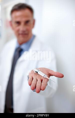 Sorridete e non vi sentirete una cosa. Colpo di primo piano di un medico che tiene in mano una siringa. Foto Stock