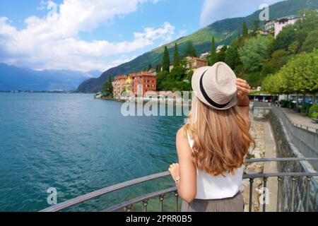 Vacanze sul Lago di Como. Vista posteriore di una ragazza rilassata che gode di un paesaggio sul lago di Como, Italia. Foto Stock