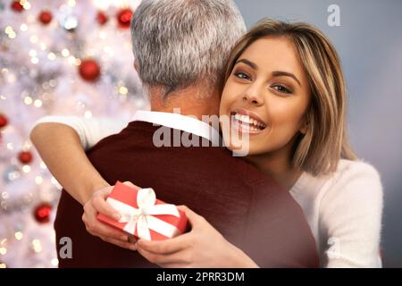 Grazie tante, papà. Una bella giovane donna che abbraccia il padre dopo aver ricevuto un regalo di Natale da lui. Foto Stock