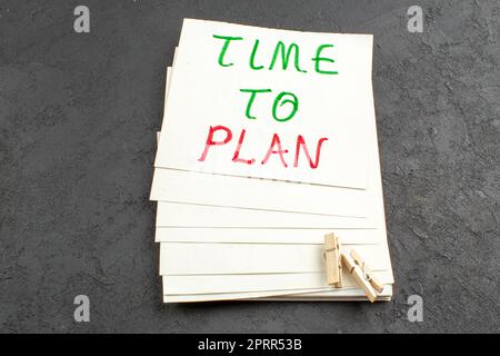 vista inferiore tempo di pianificare scritto su carta nota clothespins su sfondo nero Foto Stock