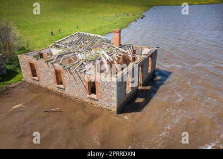 Veduta aerea di una storica fattoria in pietra bluastre in parte sommersa in un lago allagato al Cairn Curran Reservoir a Victoria, Australia Foto Stock