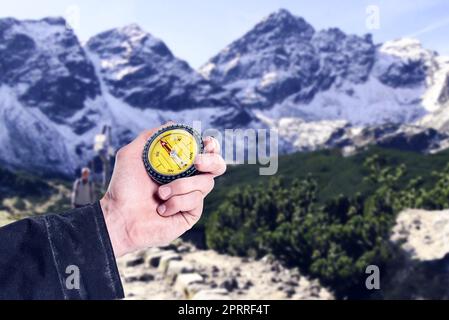 L'inferno sa sempre dove andare. Una mano di mans che tiene una bussola contro terreni estremi. Foto Stock