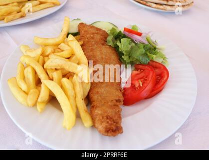 Pesce e patatine fritte. Filetto di pesce fritto con patatine fritte servito su piatto bianco con verdure Foto Stock