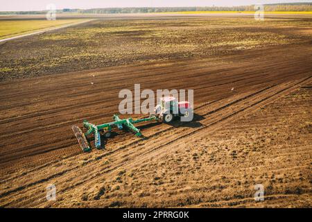 Vista aerea. Campo di aratura del trattore. Inizio della stagione di primavera agricola. Coltivatore trainato da un trattore in campagna paesaggio rurale Foto Stock