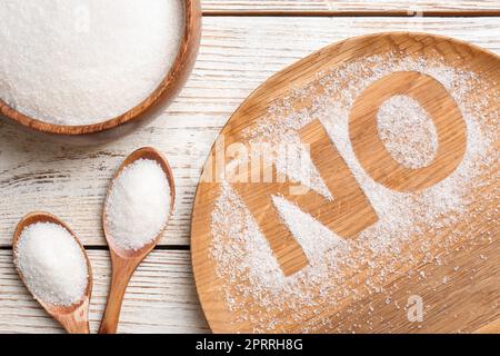 Niente zucchero. Composizione piana con granuli raffinati su tavola di legno bianco Foto Stock