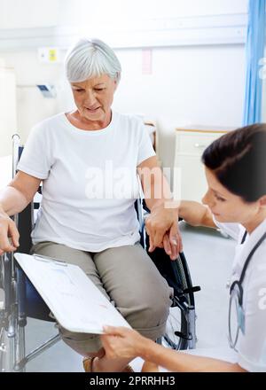 Una bella giovane dottoressa che discute i risultati con un paziente anziano. Foto Stock