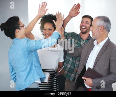 Un gruppo di colleghi positivi che si accanono mentre si trovano in ufficio. Foto Stock