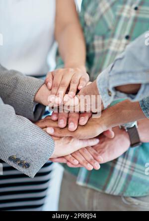 Insieme, facciamo la squadra migliore: Un gruppo di colleghi con le mani in una barzetta. Foto Stock