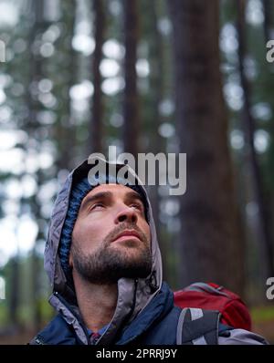 Respirare la freschezza della foresta. Ritratto di un giovane uomo che indossa uno zaino durante le escursioni nella foresta. Foto Stock