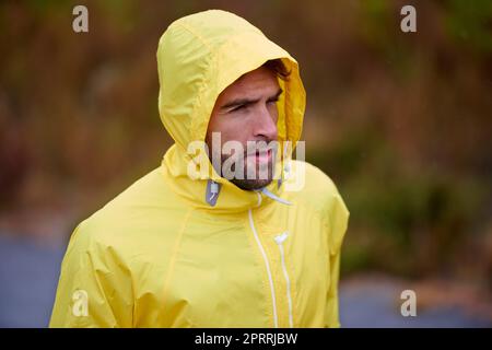 Ci vuole impegno per raggiungere i tuoi obiettivi. Un bel giovane che prende una breal mentre corre in condizioni di pioggia. Foto Stock