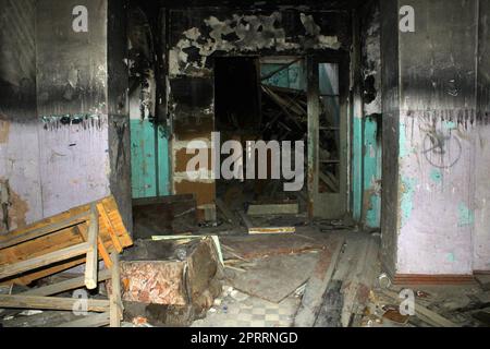 Un vecchio edificio distrutto e carbonizzato dall'interno con i resti delle cose Foto Stock