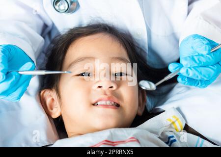 Il medico esamina la cavità orale del bambino piccolo usa lo specchio della bocca per controllare la cavità dei denti Foto Stock