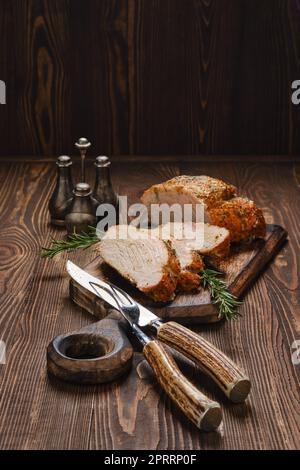 Lombata di maiale cotta in forno su tavola da portata in legno Foto Stock