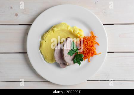 Vista dall'alto del piatto con maiale al forno con purè di patate e carota piccante Foto Stock