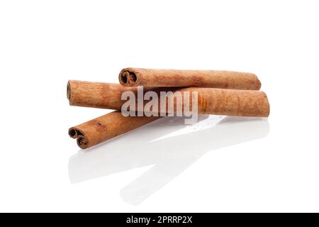 Tre bastoncini di cannella con riflesso su sfondo bianco. Foto Stock
