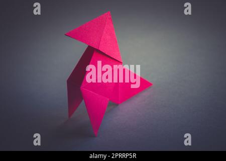 Carta rosa gallina origami isolato su uno sfondo grigio Foto Stock