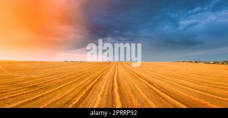 Vista aerea dell'alba al tramonto, cielo luminoso sopra il paesaggio estivo del campo di fieno al tramonto. L'erba secca tagliata trasformata in paglia non è ancora stata rimossa dal campo. Panorama Foto Stock