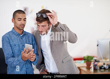 Permettetemi di esaminare più da vicino ciò che ha fatto youve. Due colleghi in ufficio che guardano un tablet digitale. Foto Stock