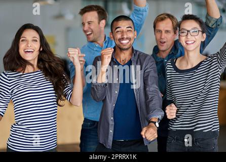 Il successo non è mai stato così buono. Un gruppo eterogeneo di membri positivi del personale festeggia insieme nel proprio ufficio. Foto Stock