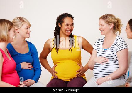 Sostentarsi l'un l'altro durante le loro gravidanze. Un gruppo multietnico di donne incinte sorridenti mentre si siedono insieme in cerchio. Foto Stock